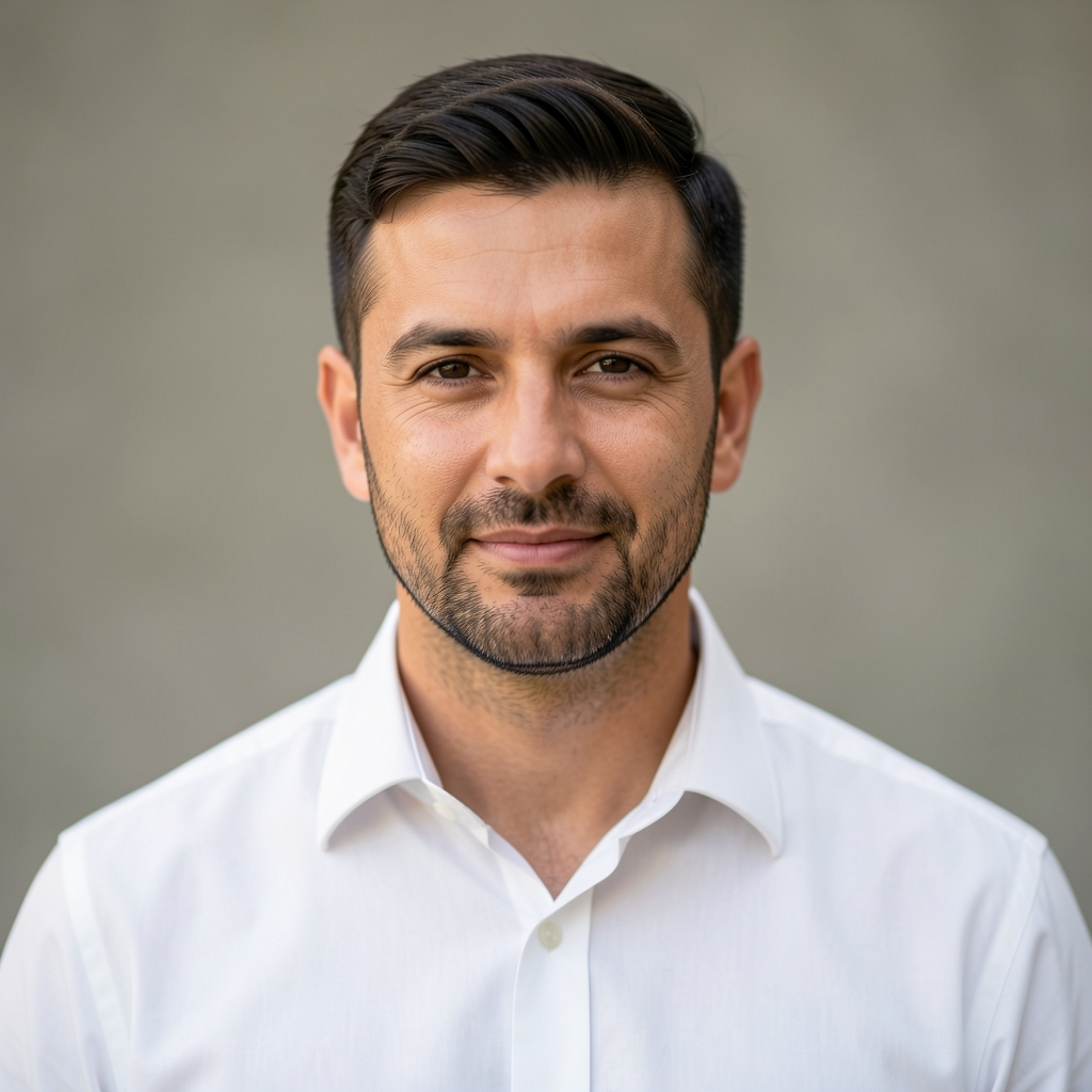Headshot of a man in his late thirties, natural studio lighting with a neutral background, composed professional expression, white shirt